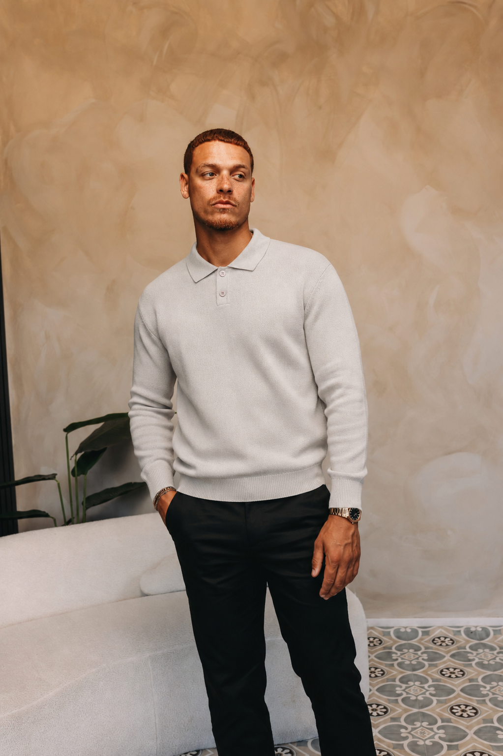 Model in de grijze Knit Longsleeve Polo met een zwarte broek