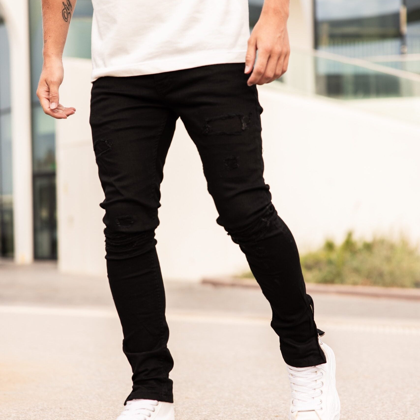Model in de zwarte Napoleon Black Jeans met een wit T-shirt en witte sneakers