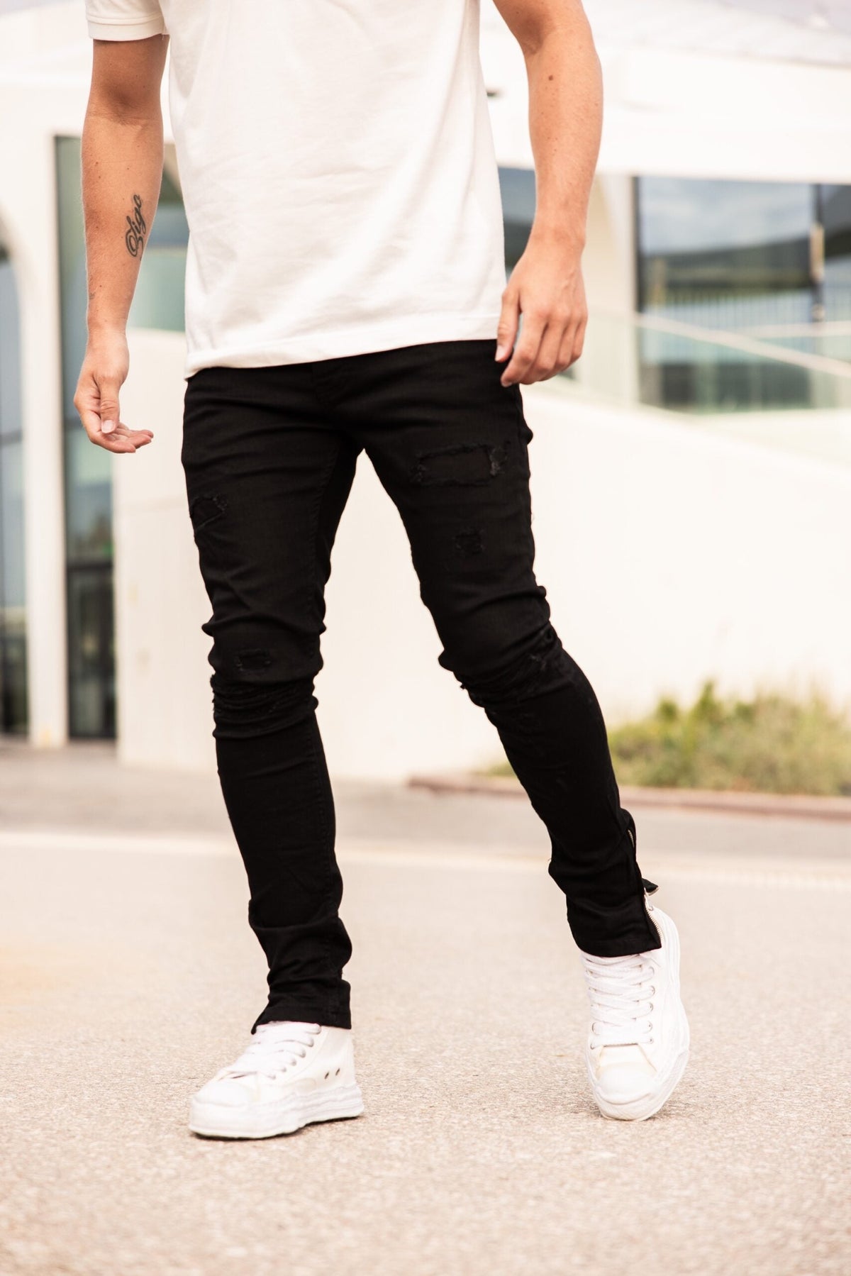 Model in de zwarte Napoleon Black Jeans met een wit T-shirt en witte sneakers
