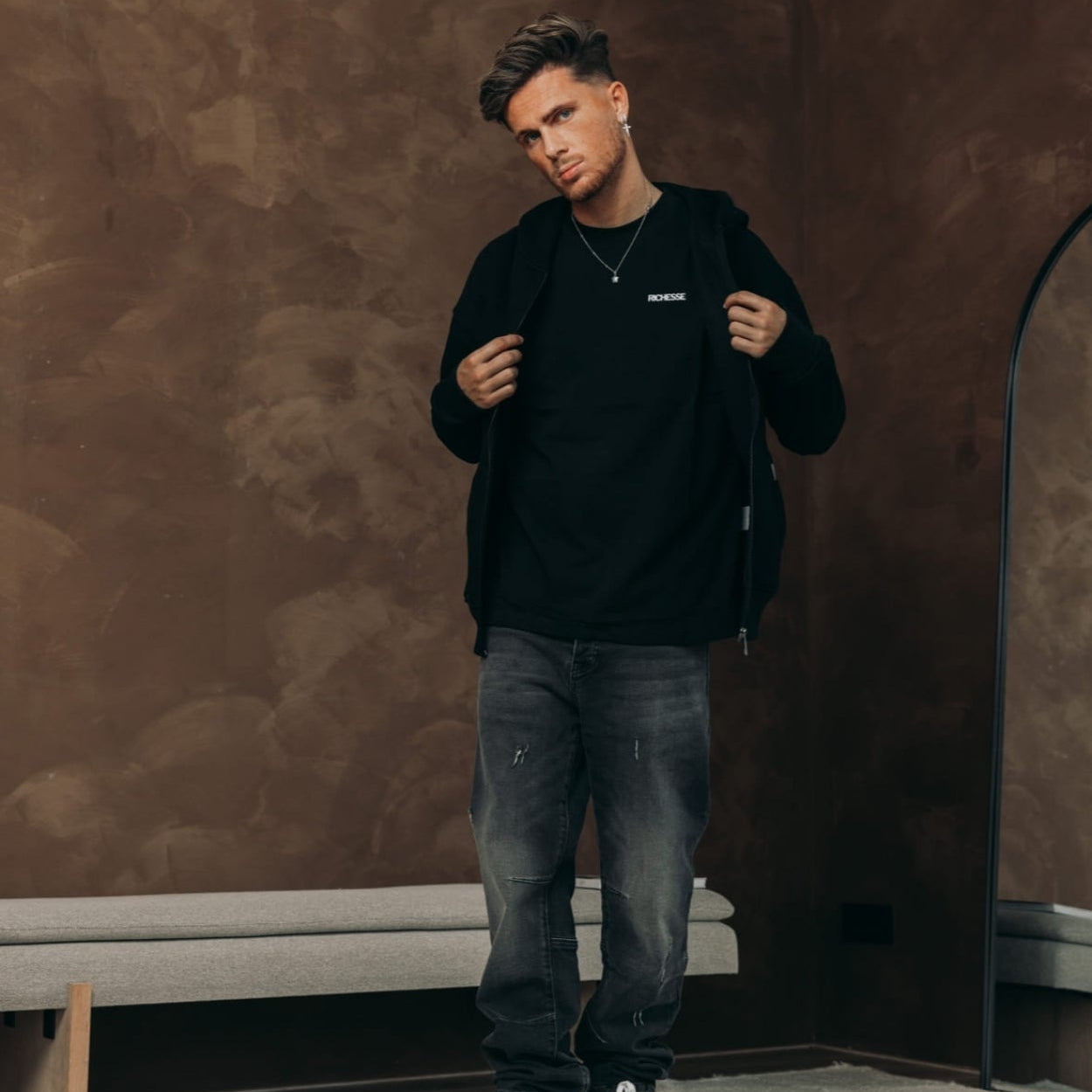 Model in de Bullet Black Baggy Jeans met een zwarte zip hoodie en sneakers