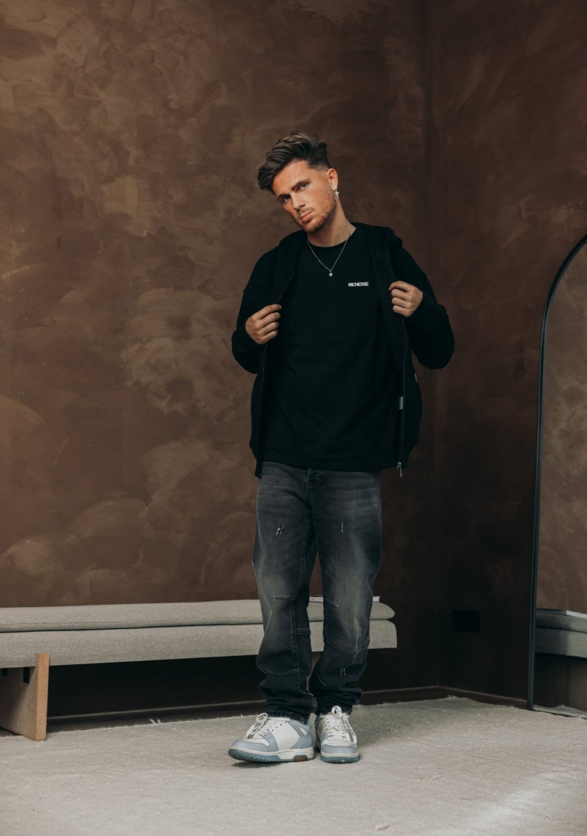 Model in de Bullet Black Baggy Jeans met een zwarte zip hoodie en sneakers