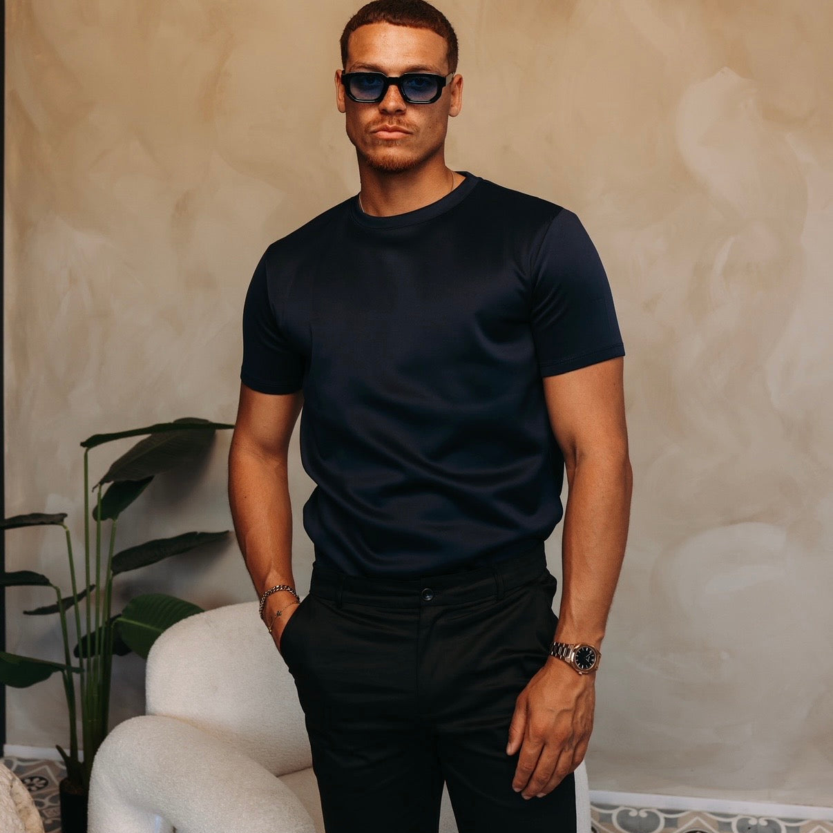 Model met zonnebril in het navy Gloss Essential Shirt en een zwarte broek