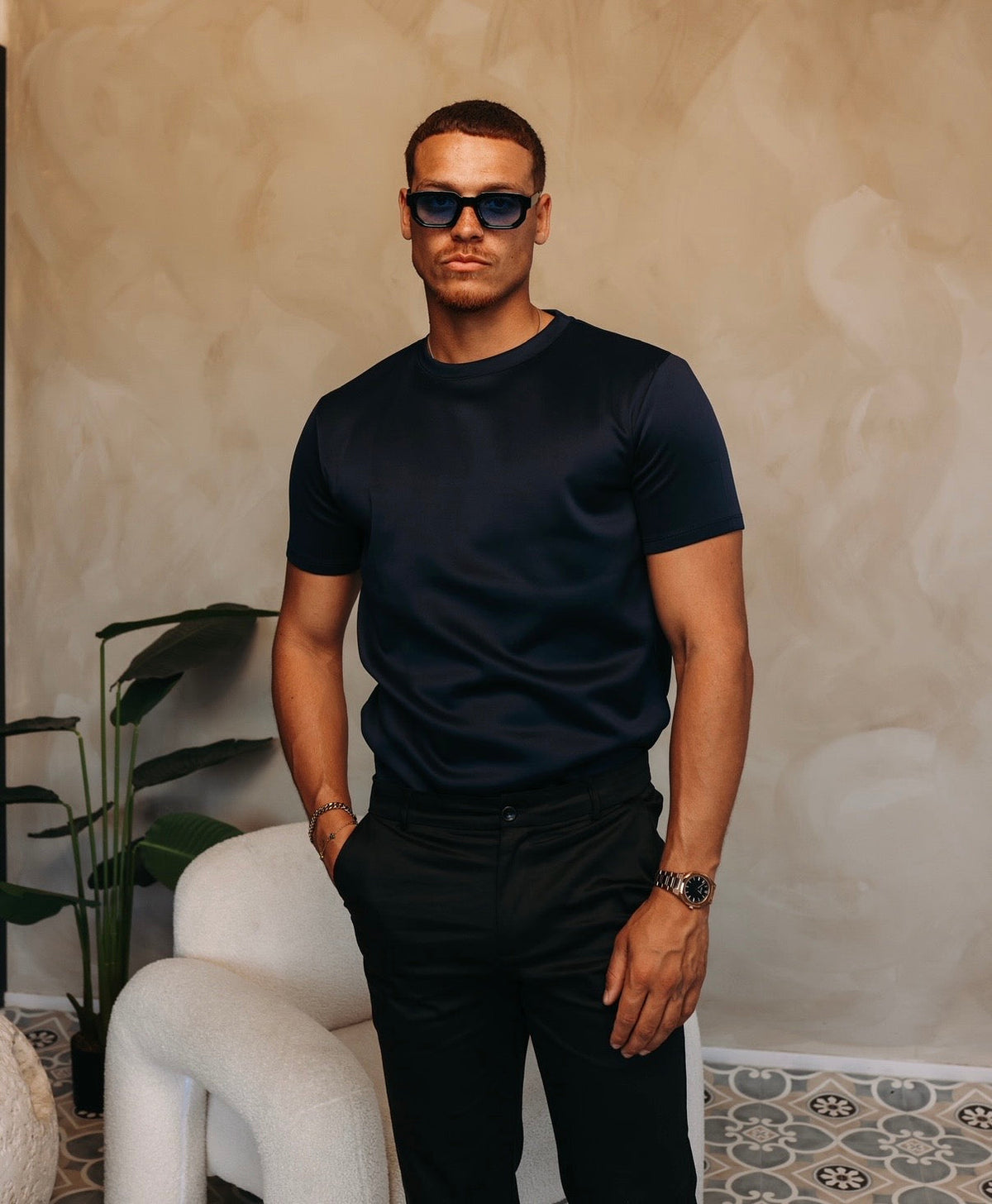 Model met zonnebril in het navy Gloss Essential Shirt en een zwarte broek