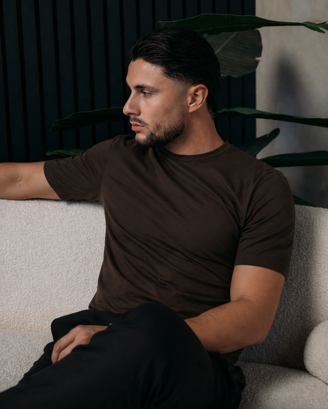Model in het Shiny Essential Shirt in deep brown, zittend op een witte bank