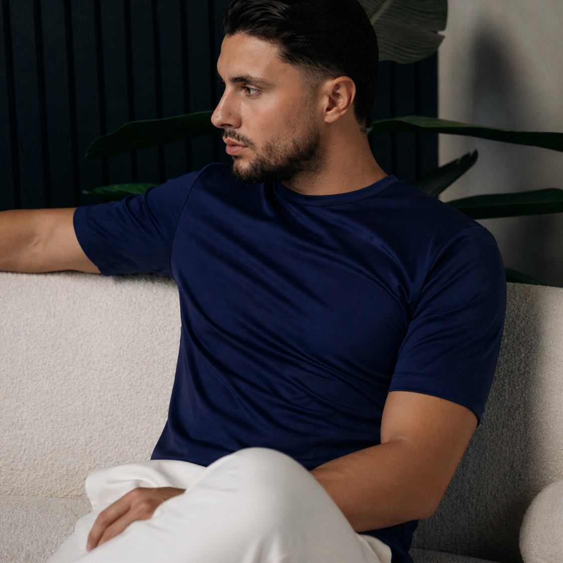 Model in het navy Shiny Essential Shirt, zittend op een witte bank