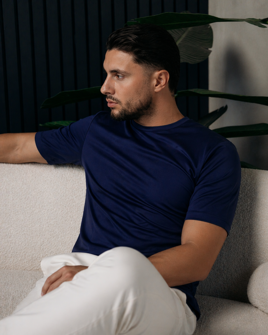 Model in het navy Shiny Essential Shirt, zittend op een witte bank